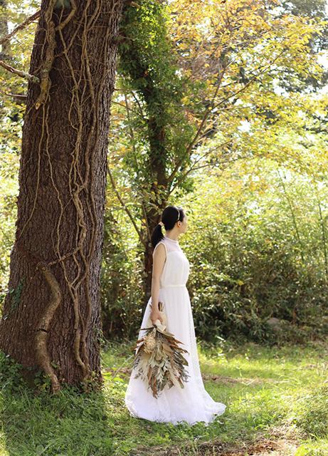 ウエディングドレスを着て木の下に立つ女性